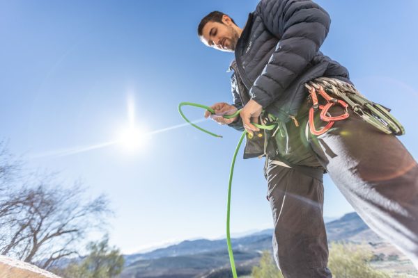 Pánská izolační bunda Rab Cirrus Flex při navazování se na lano před skalním lezení.